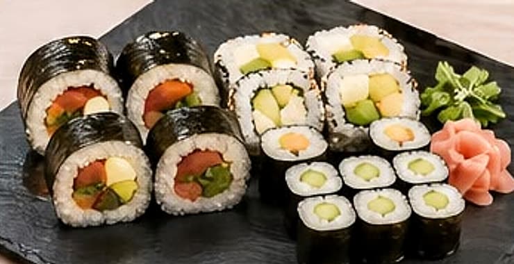 Zestaw Sakura na kamiennej płycie: futomaki wege, uramaki z avocado i hosomaki z ogórkiem.